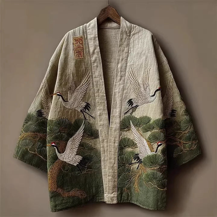 Open-front kimono jacket with wide sleeves, beige and green crane and pine tree print, front view on hanger