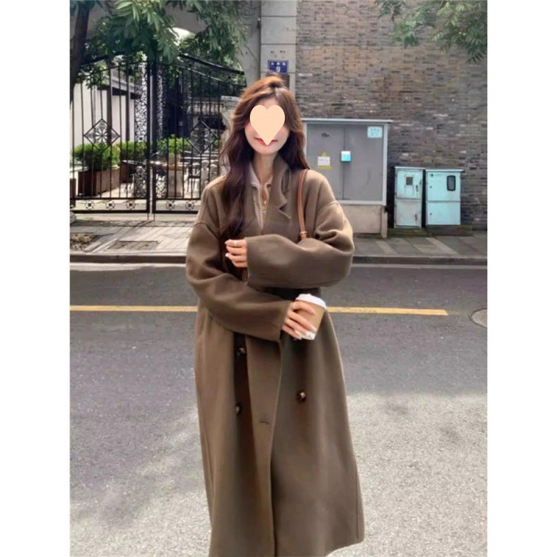 Long oversized double-breasted coat in caramel mocha, worn by a model on a street, front view with arms folded