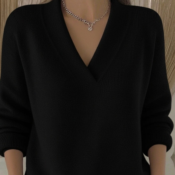 Black relaxed V-neck knit sweater, close-up front view on a model showing the neckline and chest