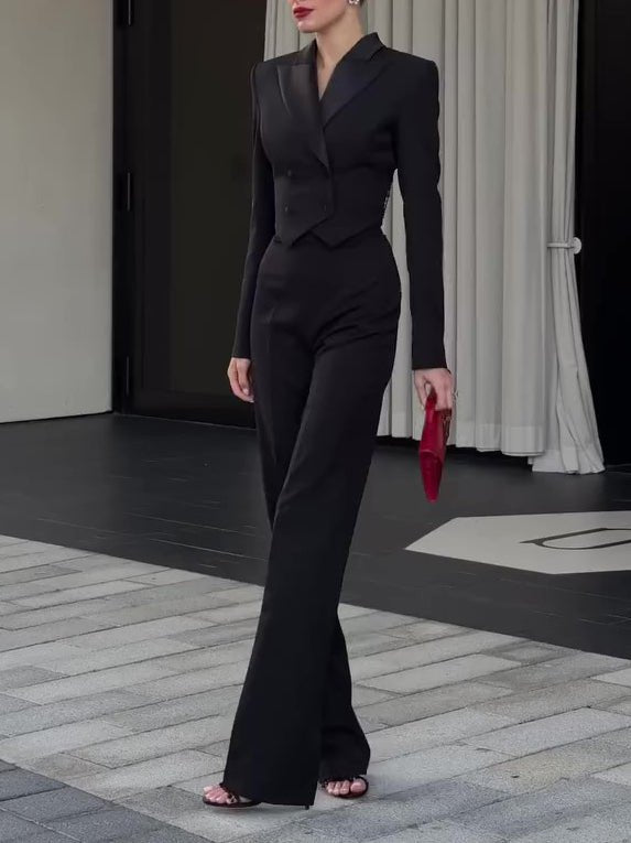 Model walking in the black trouser suit with heels and a red clutch