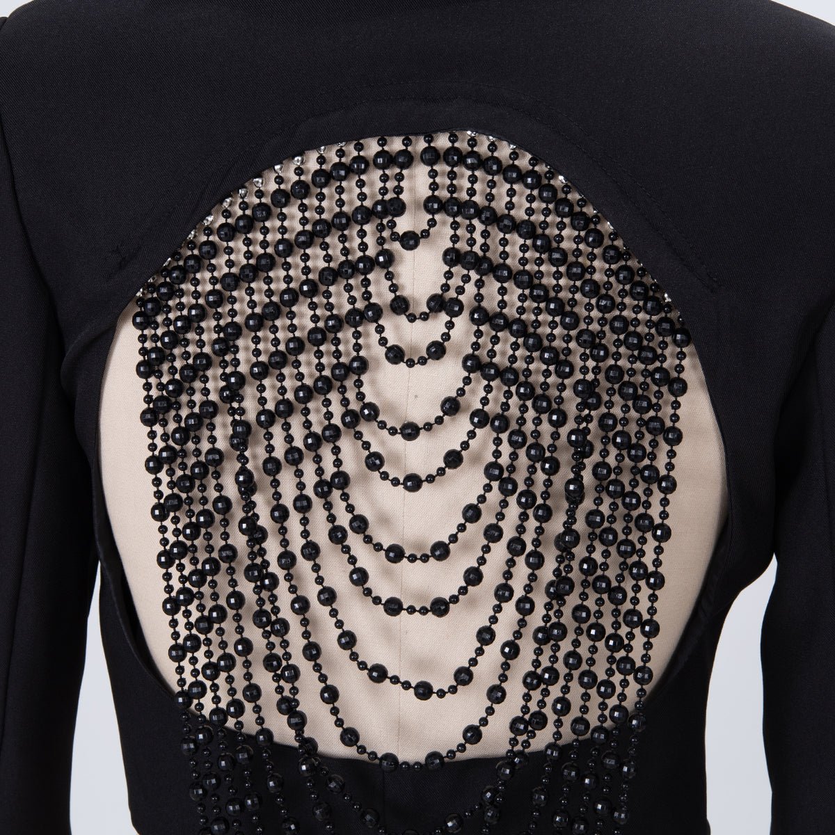 Close-up of the bead strands across the open back on a dress form