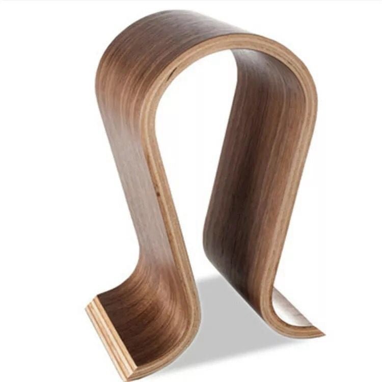 Omega headphone stand in walnut colour seen at an angle, with pale ply layers along the edge