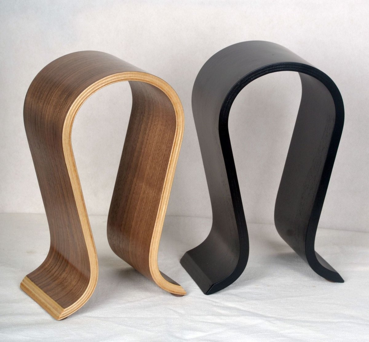 Walnut-coloured and black headphone stands side by side