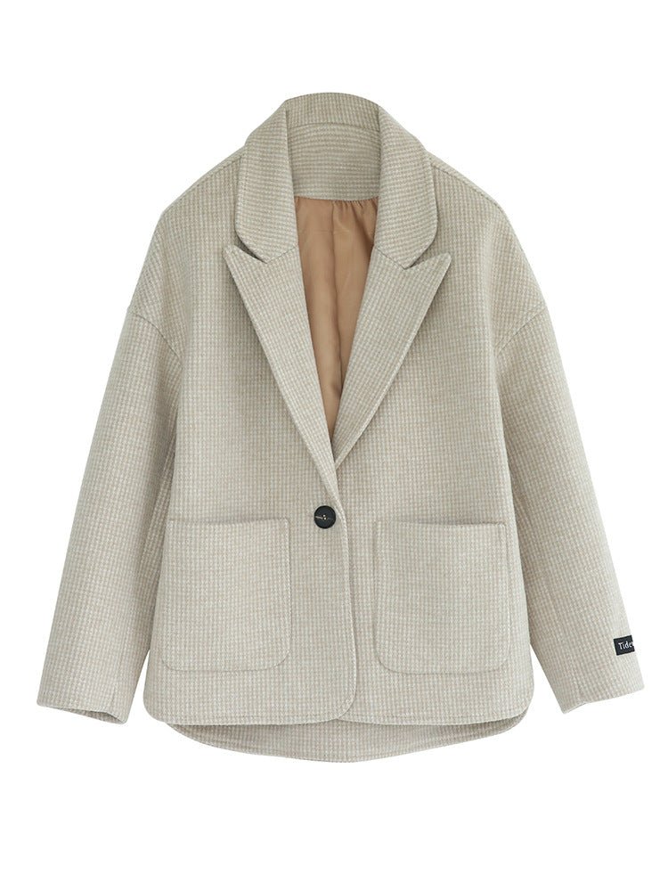 Front of the boxy houndstooth blazer: notch lapel, one dark button, two patch pockets, tan lining