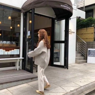 Woman in the beige blazer walking out of a shop on a city street
