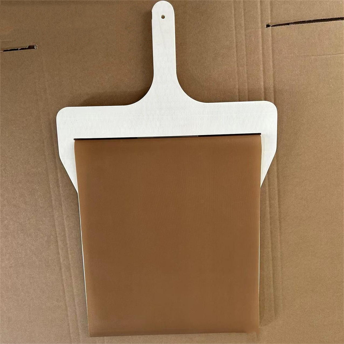 Sliding pizza peel with wooden frame, top view on brown cardboard surface