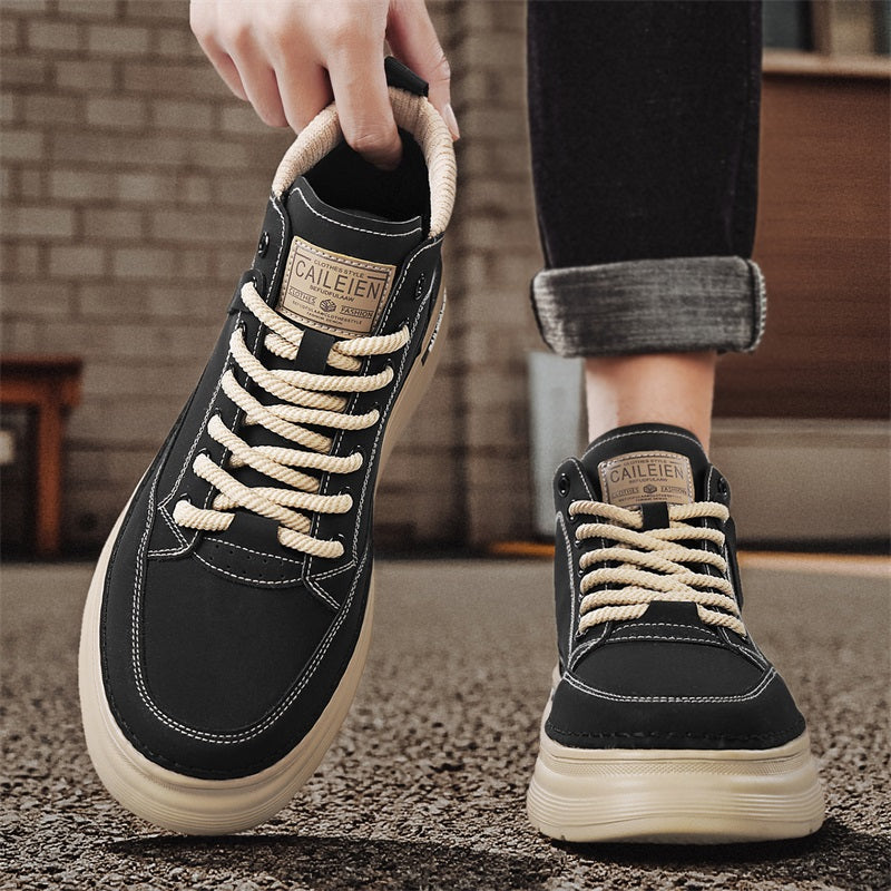 Men's high-top lace-up sneaker boots in black, worn on feet, one shoe lifted, outdoor urban setting