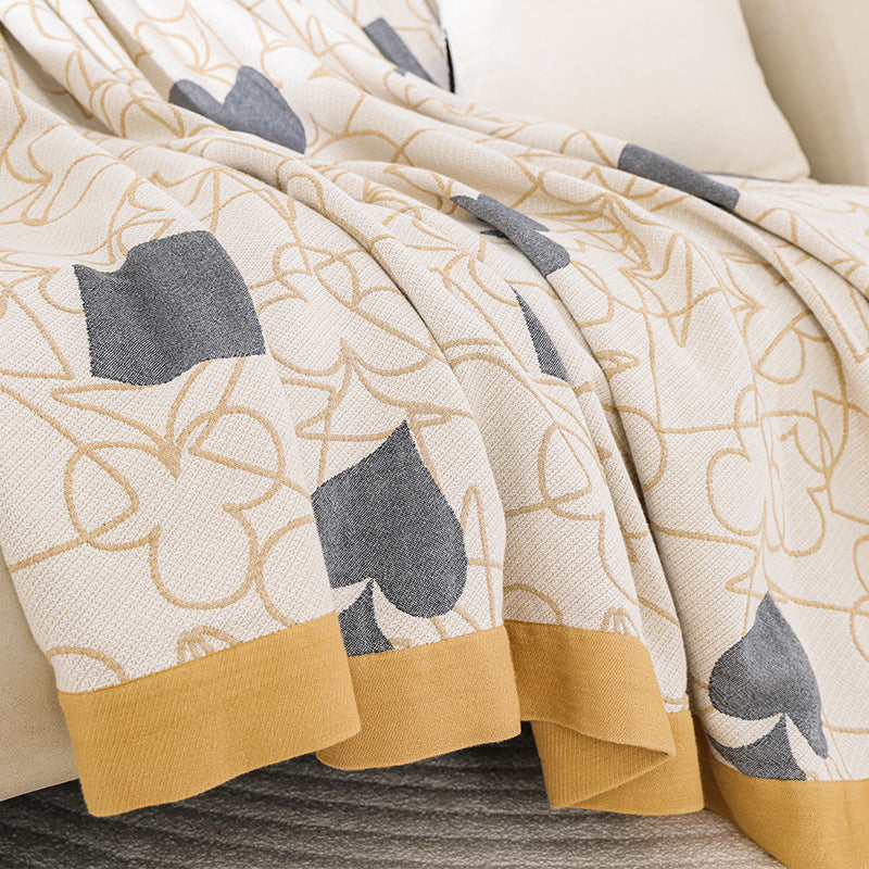Detail of the mustard-yellow border and grey spade shapes on the edge of the card-suit gauze blanket