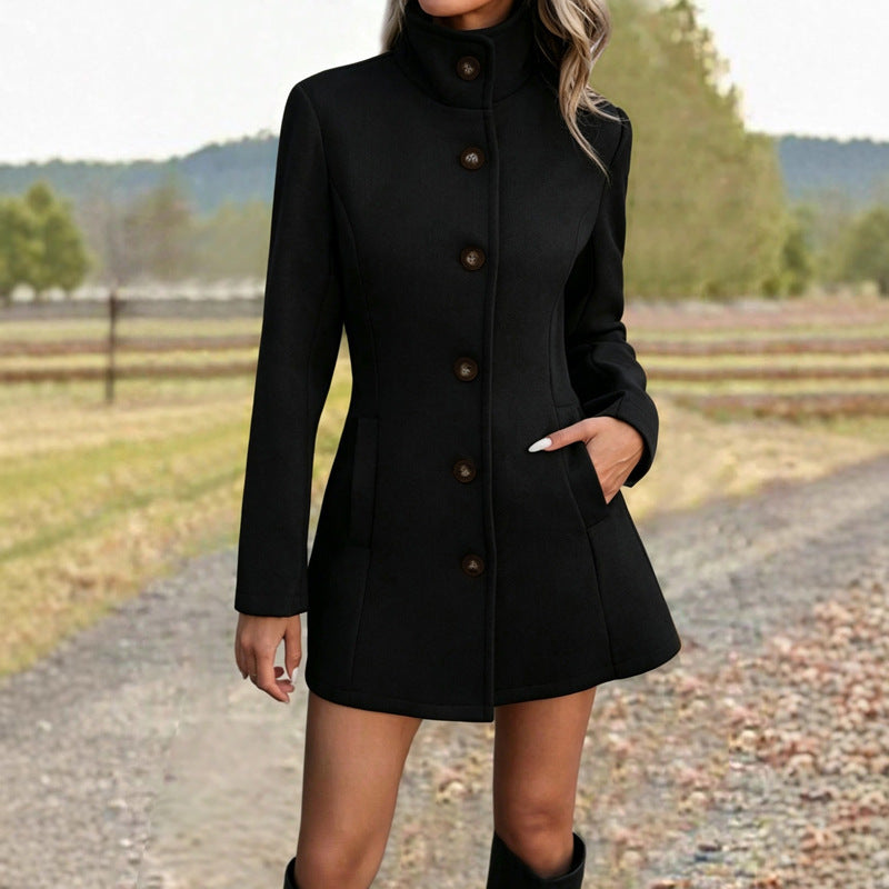 Fitted stand-collar coat in black, single-breasted with button front, worn by model on gravel path
