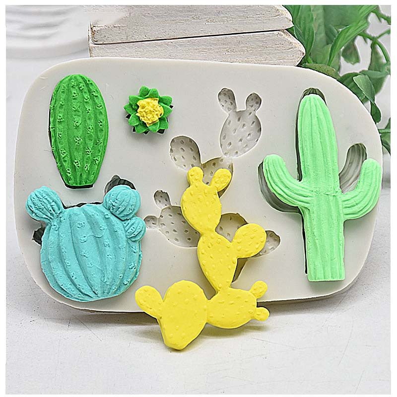 Cactus and succulent silicone mould in white with green, blue, yellow and light green cactus shapes placed on top, flat lay