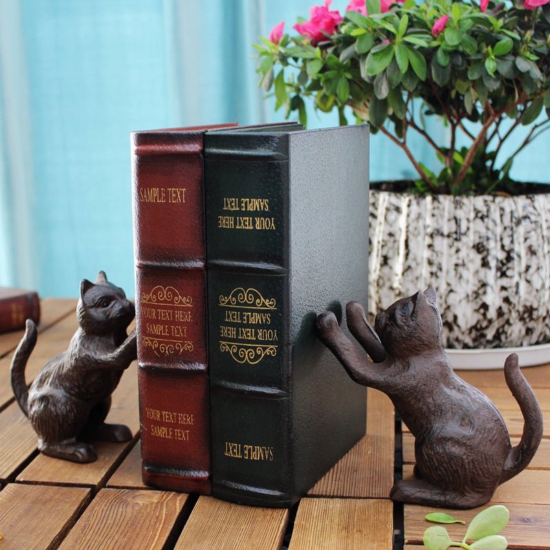 Cast-iron cat bookends holding two books upright on a wooden table