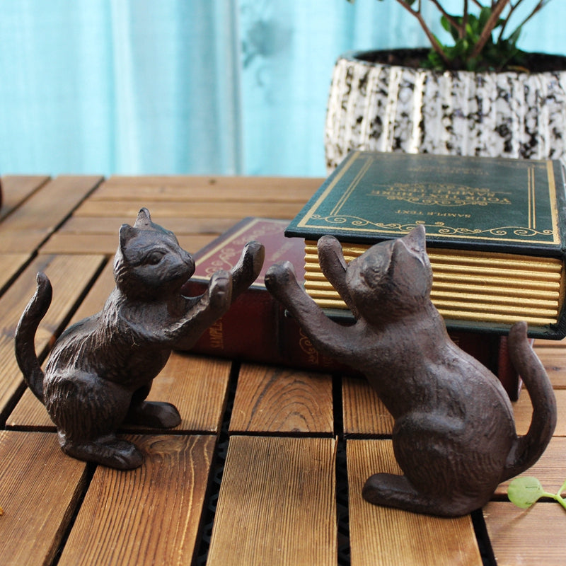 Cast-iron cat bookends, dark brown, facing each other with raised paws, side view, on wooden surface