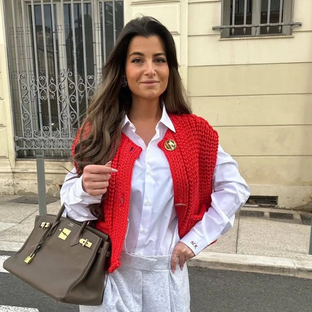 Red chunky knit vest worn over a white shirt in the street