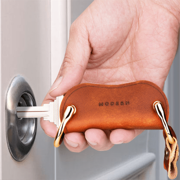 Hand unlocking a door with a key swung out of the brown key organiser