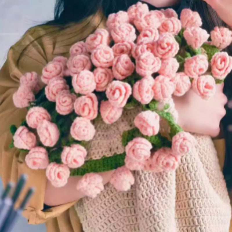 Crochet flower bouquet blanket with light pink roses, folded into a bouquet and held by a person