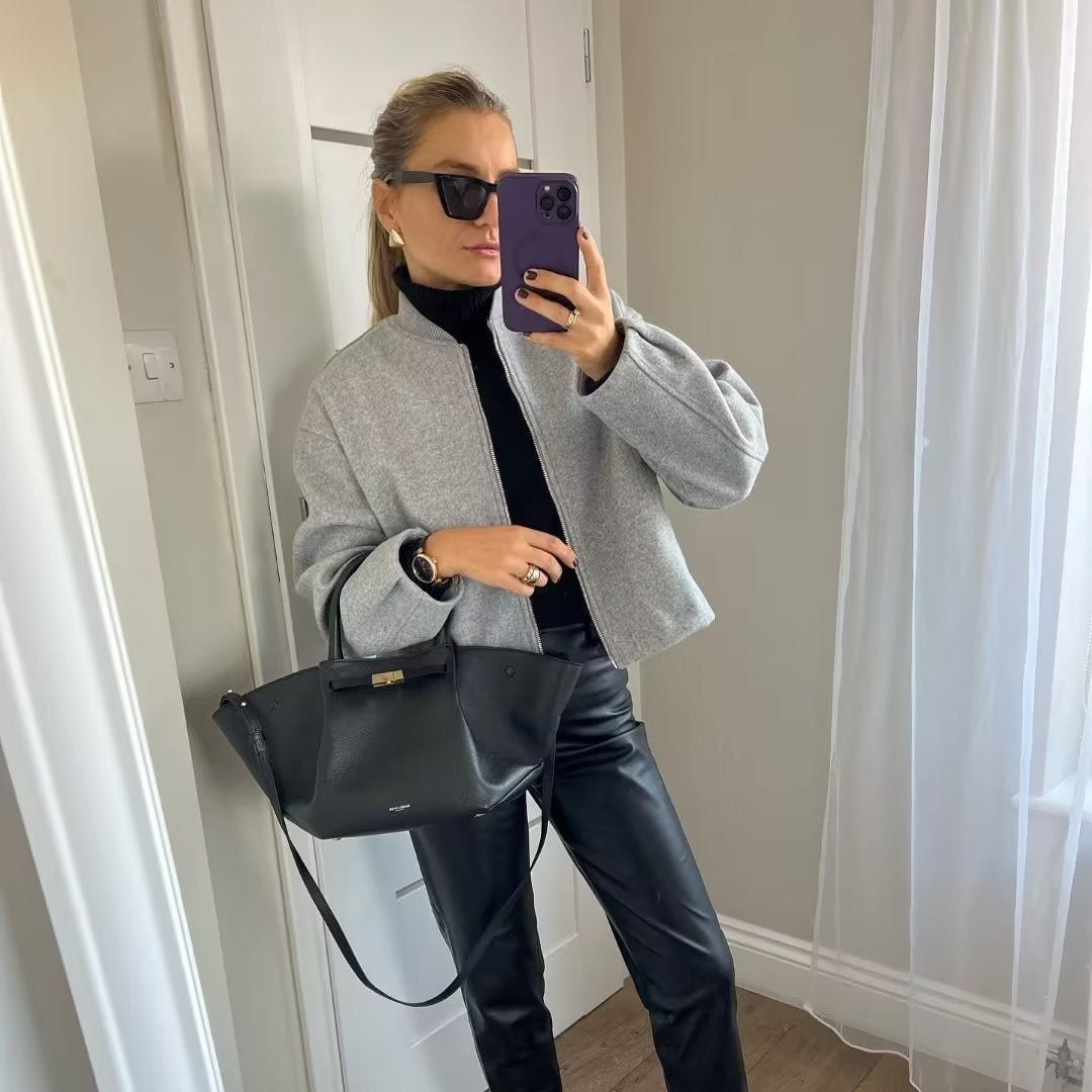 Woman taking a mirror photo in the grey cropped bomber jacket with a black roll neck and a large black bag