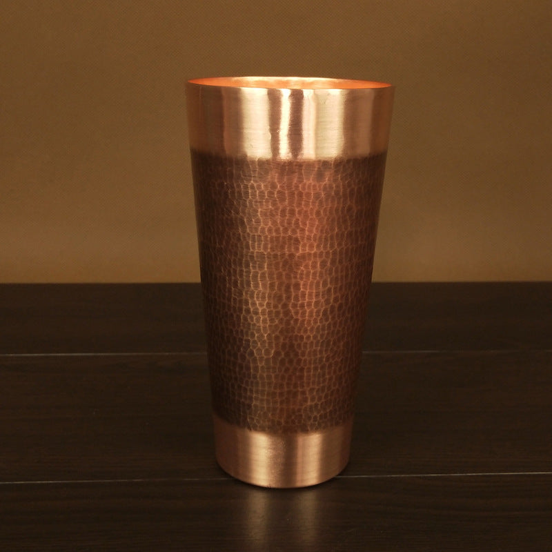 Straight hammered copper beer tumbler with textured surface, on dark surface
