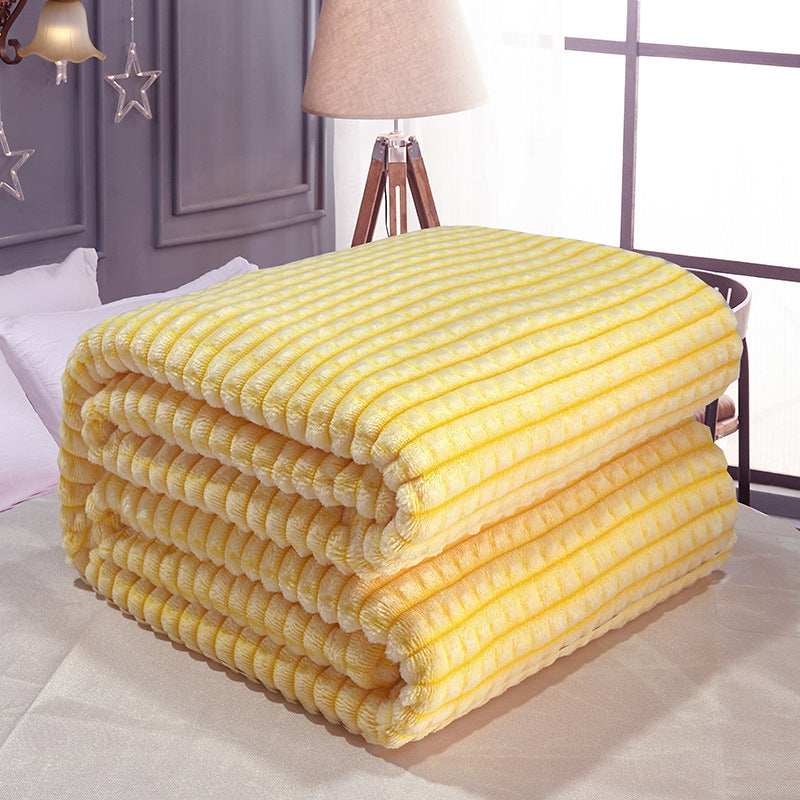 Stacked folded waffle-knit coral fleece throw blanket in lemon yellow, placed on a bed near a window and lamp