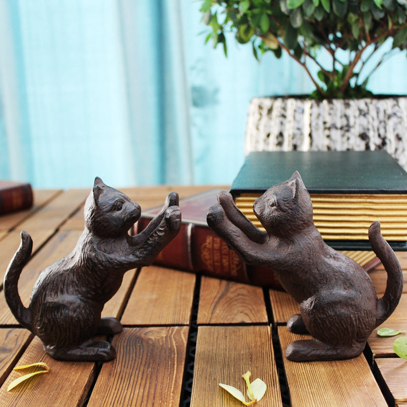 Cast-iron cat bookends, dark brown, facing each other with raised paws, front view, on wooden surface