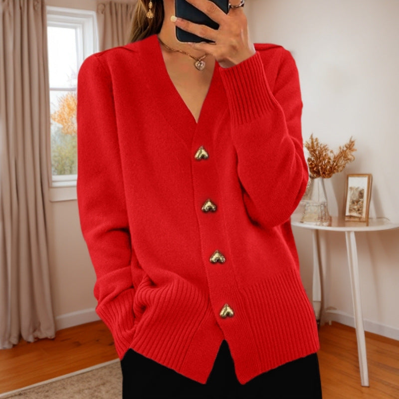 V-neck knit cardigan in red with heart-shaped buttons, worn by a model in a room with wooden floor