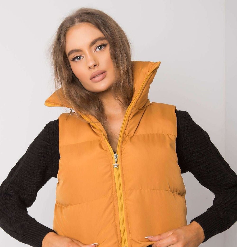 Dark yellow quilted vest with a high zipped collar, worn over a black knit, front view