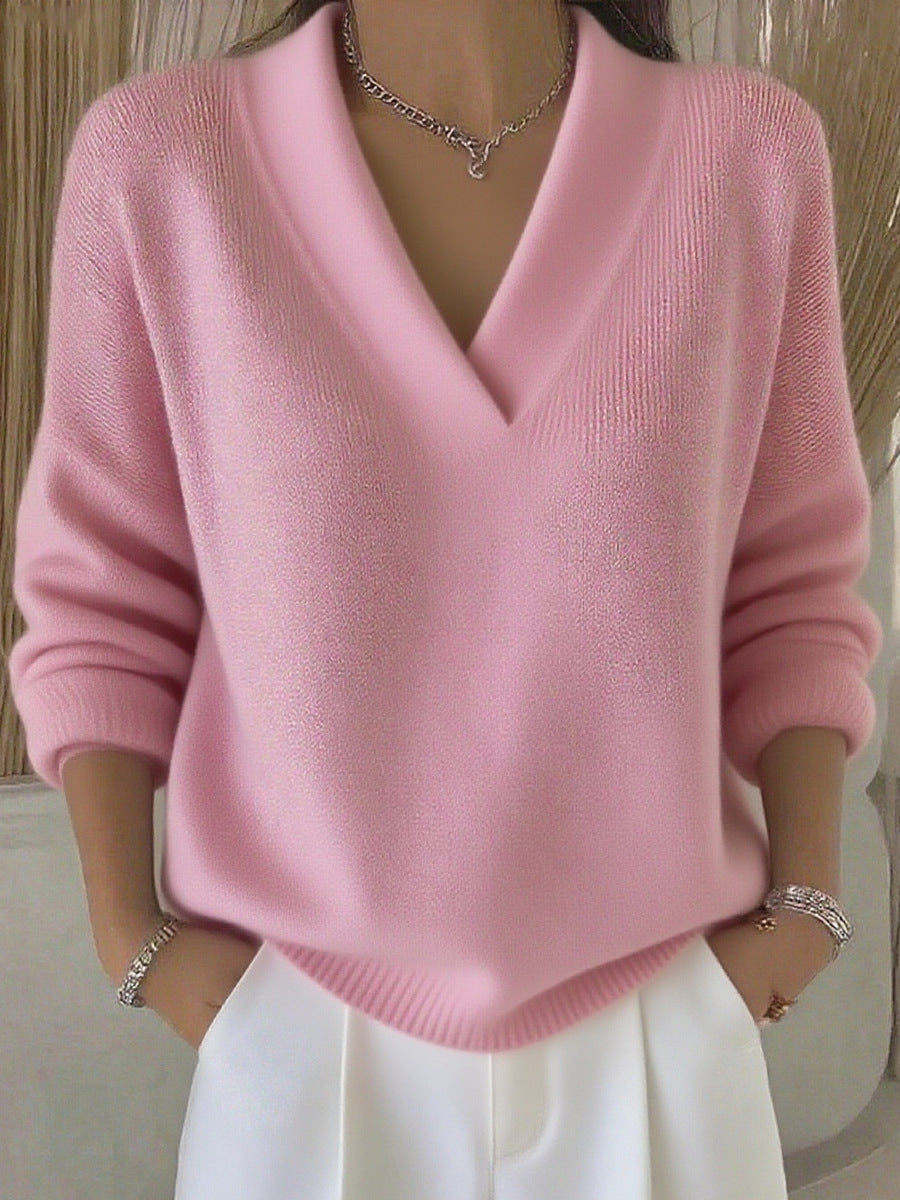 Pink relaxed V-neck knit sweater worn by a model with white trousers, front view