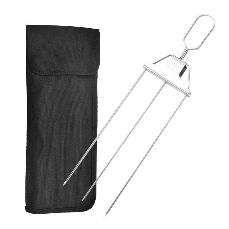Three-prong stainless steel skewer with slide-off pusher next to a black fabric storage bag on a white background