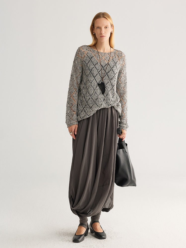 Full-length view of the grey open-knit jumper with a long dark grey draped skirt, black bag and black shoes