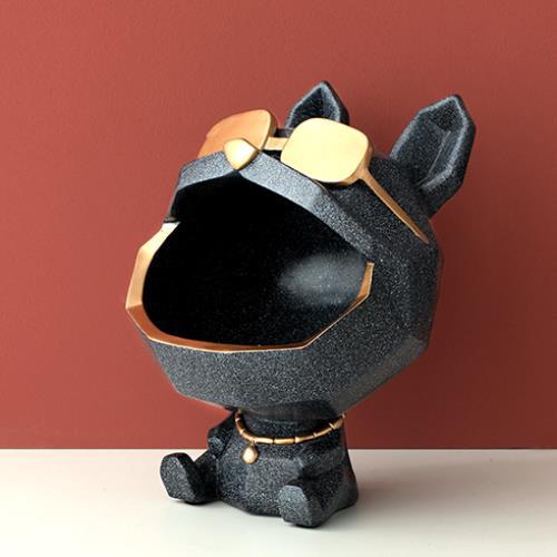Speckled black dog figure with an open mouth, gold-tone sunglasses and collar against a red wall