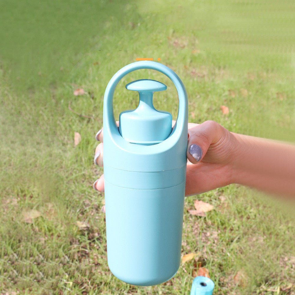 Hand holding a closed light teal dog poop picker above a lawn