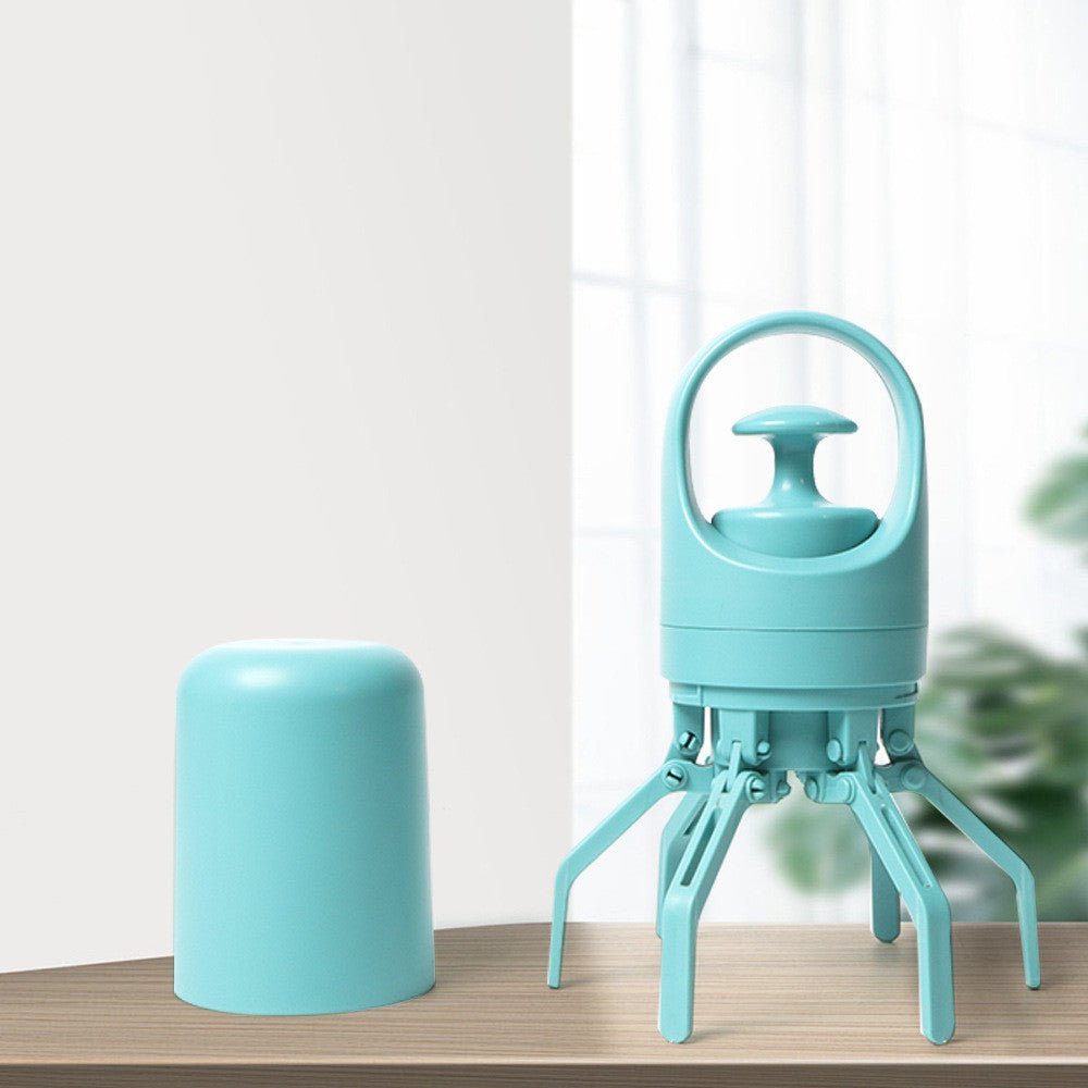 Light teal poop picker standing on its open claws on a table, with the bottom cap beside it