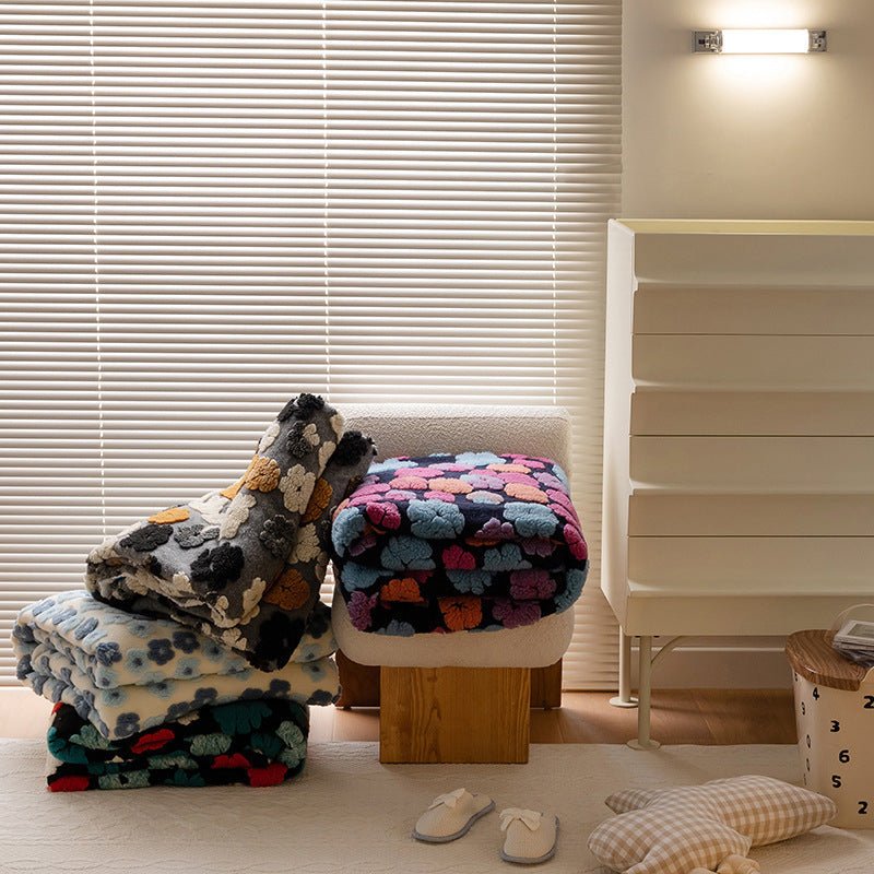 Pile of jacquard flower blankets in dark multicolour designs on a stool