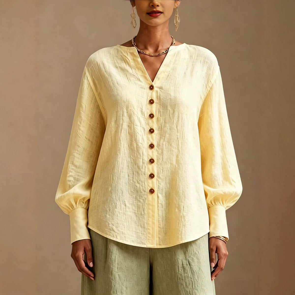 Yellow V-neck lantern-sleeve blouse with wood-tone buttons, front view on model