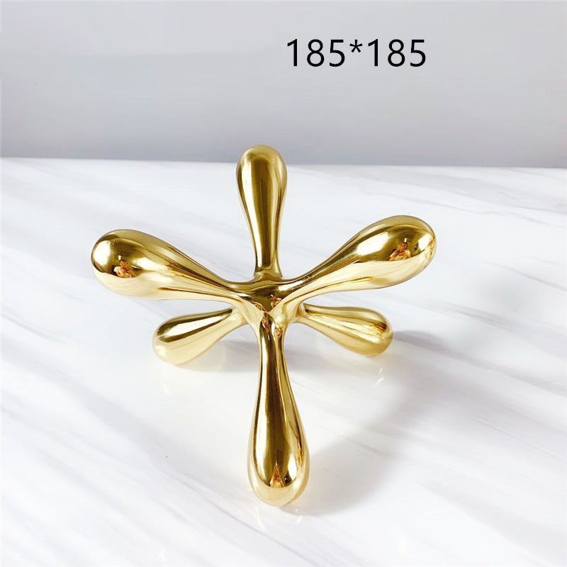 Gold-tone metal jacks sculpture, 185x185 mm, front view, on marble surface