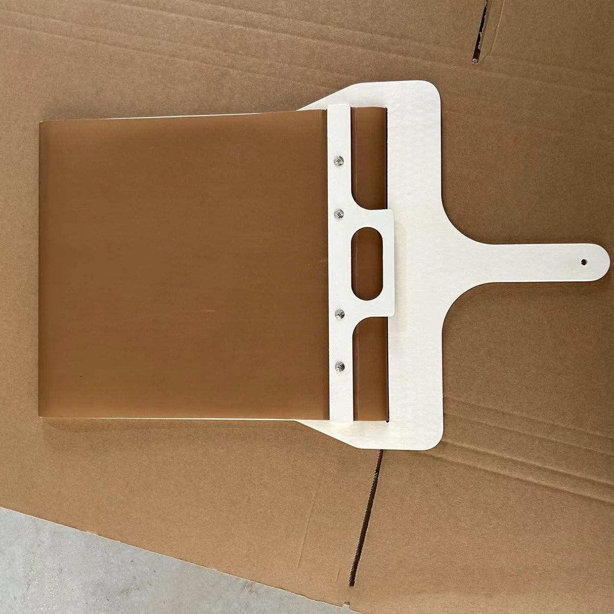 Sliding pizza peel with wooden frame, angled top view on brown cardboard