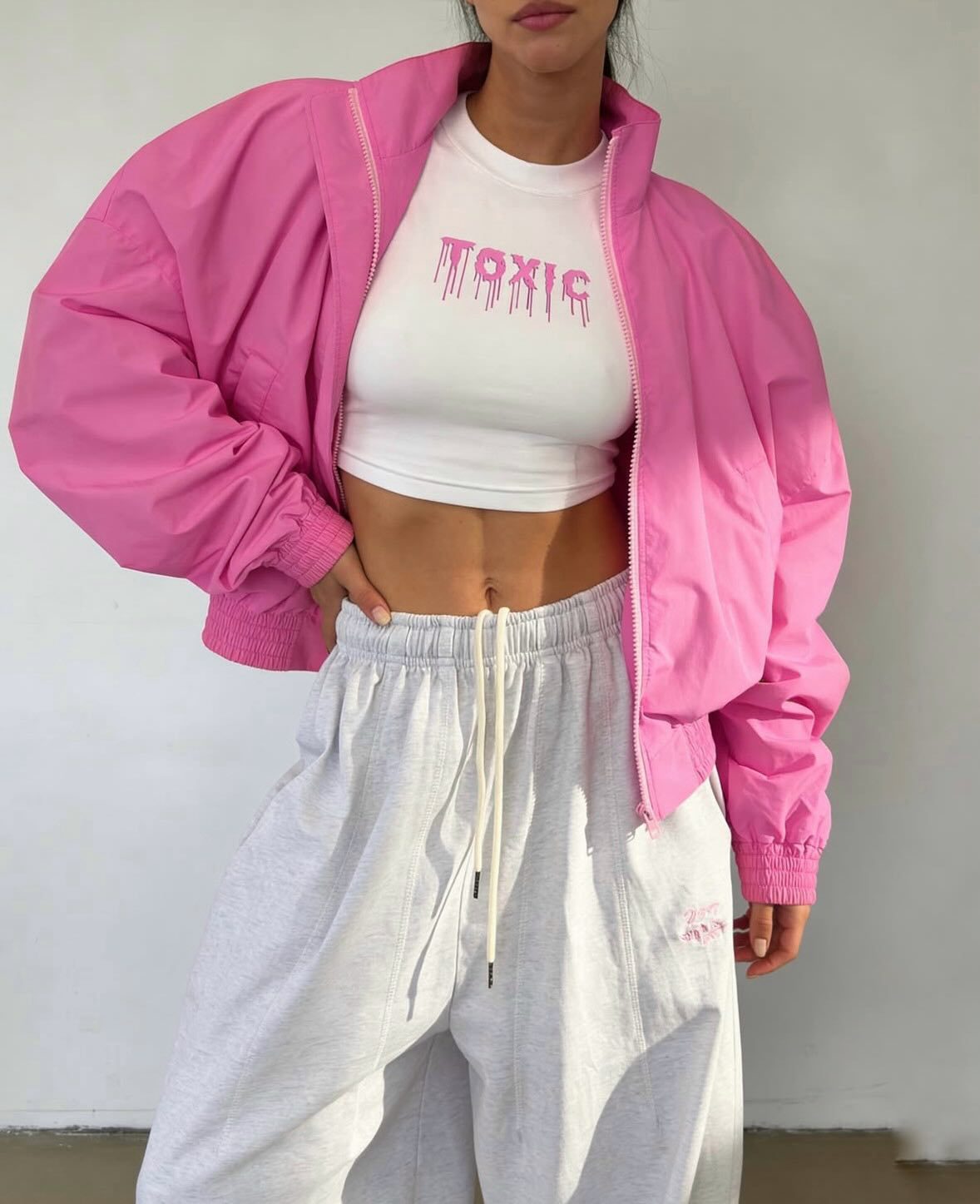 Bright pink cropped bomber jacket, front view on model, full zip, long sleeves, elasticated cuffs and hem