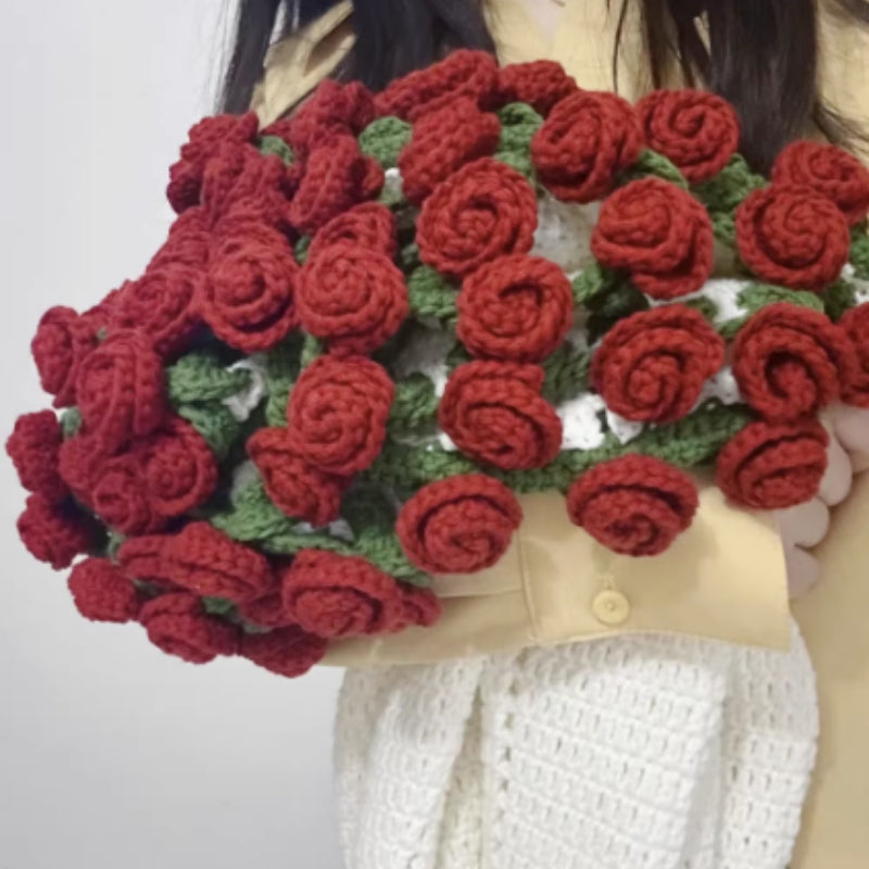 Crochet flower bouquet blanket in red roses, folded into a bouquet shape, held by a person wearing a light top, indoors