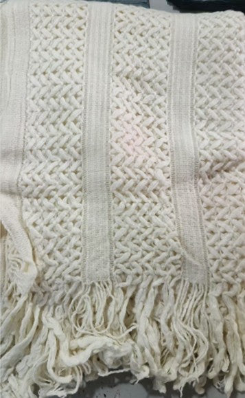 Close-up of chunky lattice knit throw in white with tassels, flat lay detail