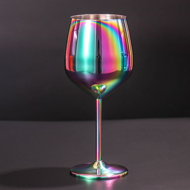 Rainbow-colored stainless steel wine glass standing upright on dark surface, reflecting multicolored light