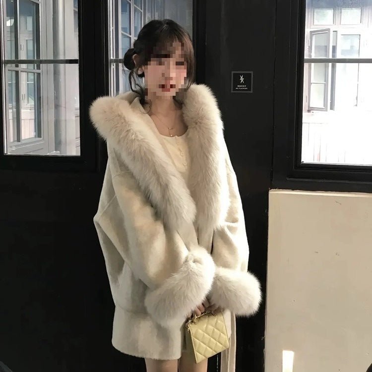 Woman in an oversized cream coat with faux fur along the collar and front, holding a small quilted bag