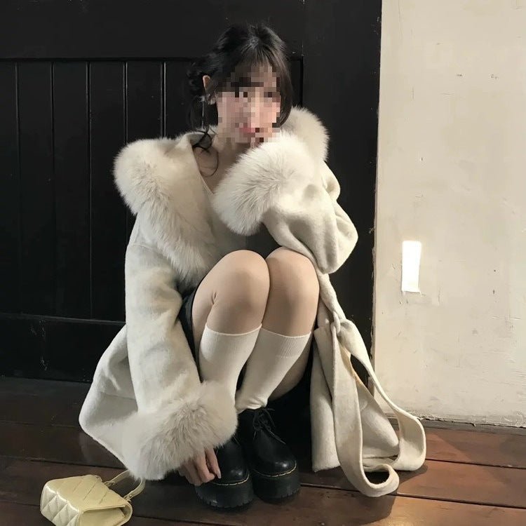 Model crouching in the cream coat, a matching tie belt hanging loose at the side