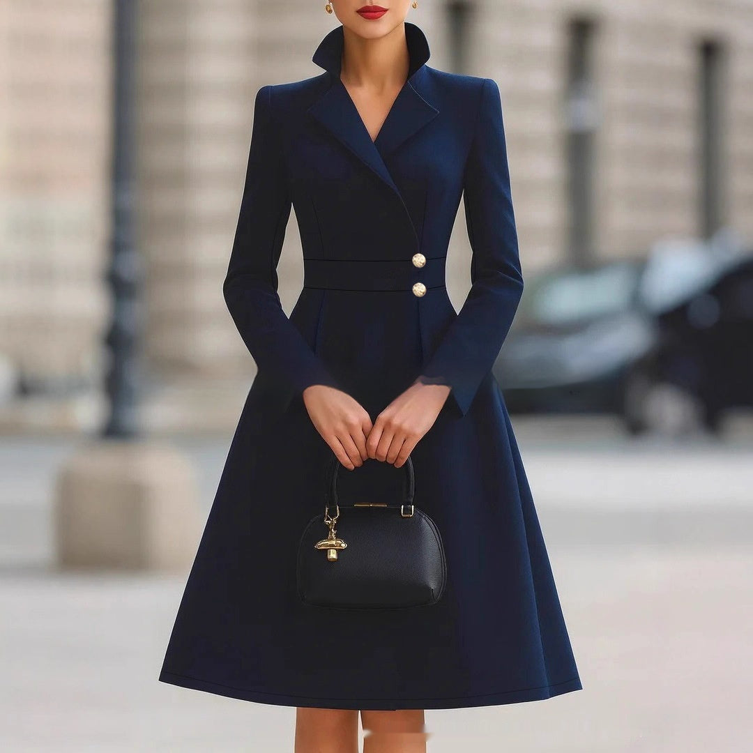 Navy double-breasted coat dress with gold-tone buttons, front view on model, hands clasped, holding black handbag, urban