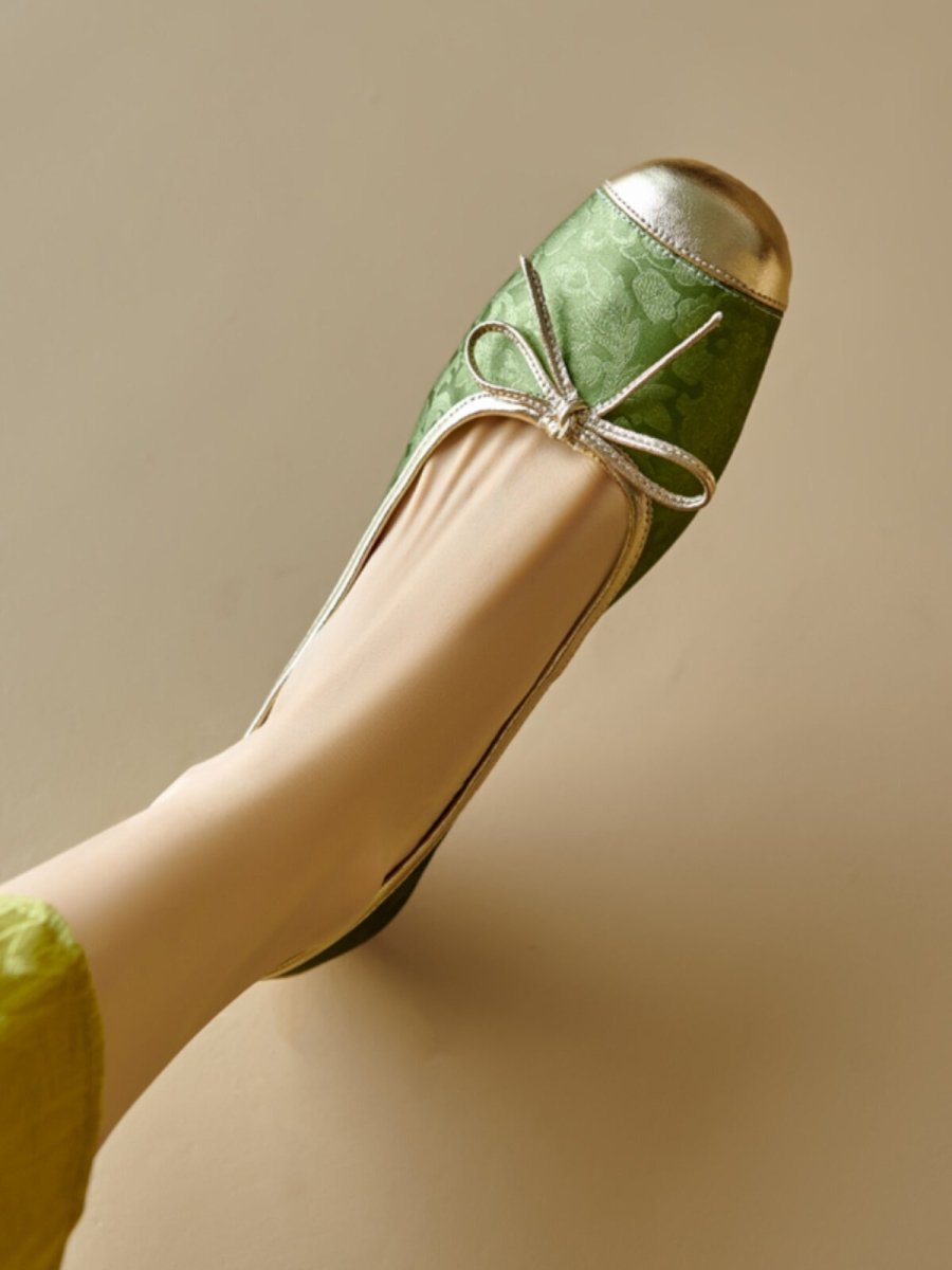 Green floral ballet flat with metallic toe cap and bow, worn on foot, side view
