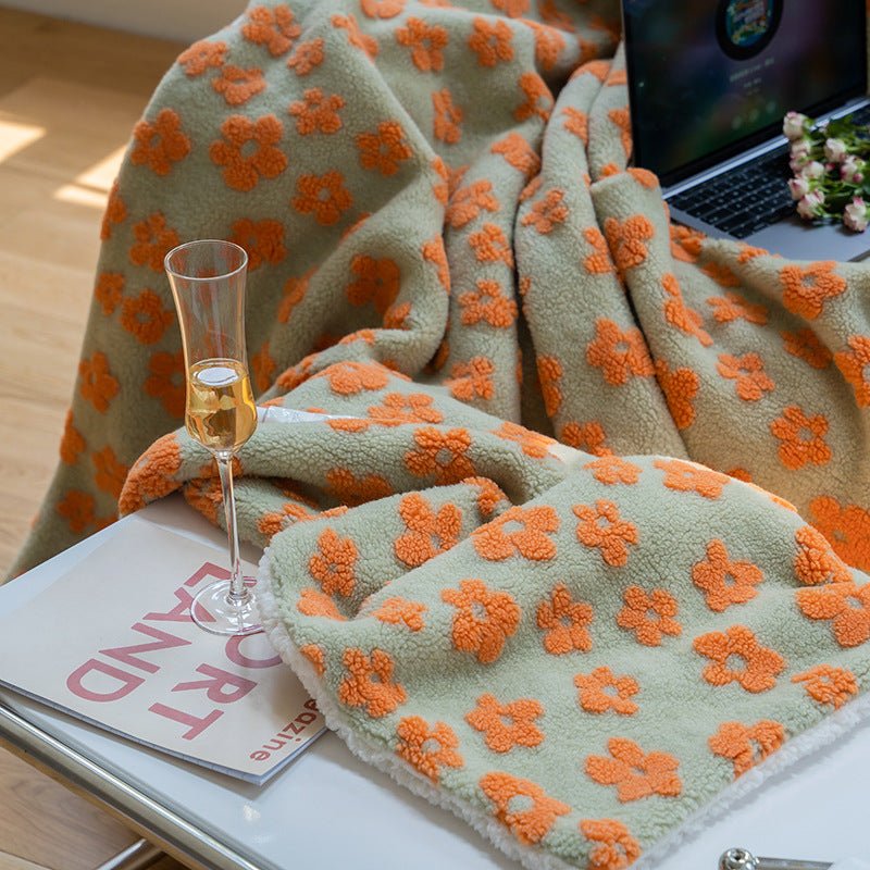 Floral jacquard sherpa blanket in sage green with orange flowers, draped over a lap