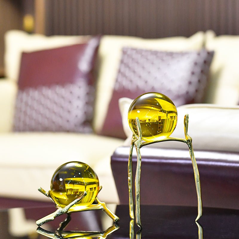 Amber glass balls on a low and a tall stand on a dark glossy table in a living room