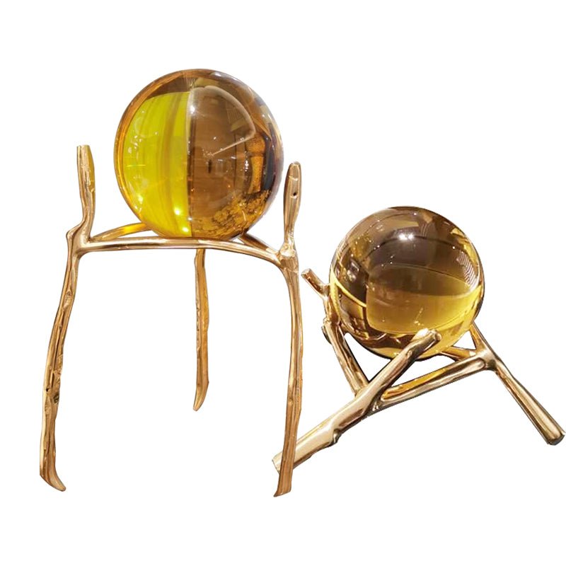 Two amber glass balls on gold-tone branch stands, one tall and one low, on a white background