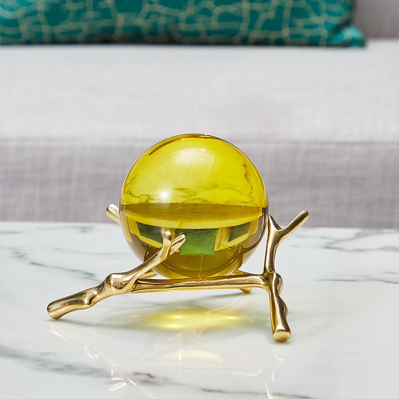 Amber glass ball on the low branch stand on a white marble table