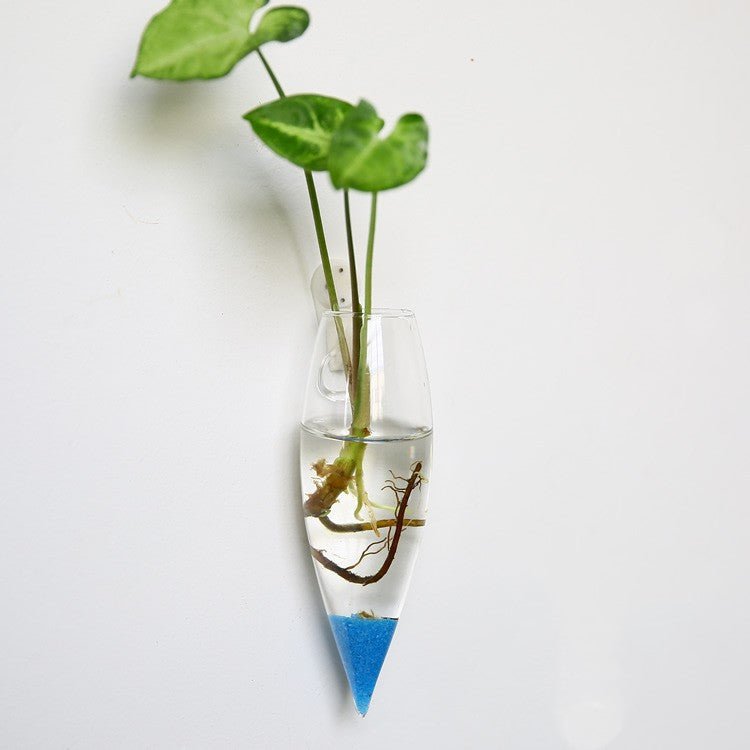 Narrow cone-shaped glass wall vase with blue sand in the tip and a green cutting