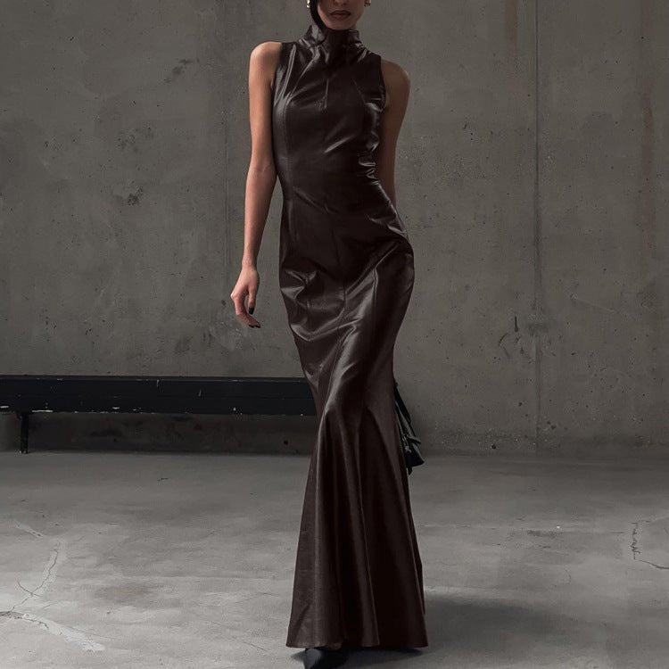Brown maxi dress with stand collar and mermaid hem, worn against a concrete wall