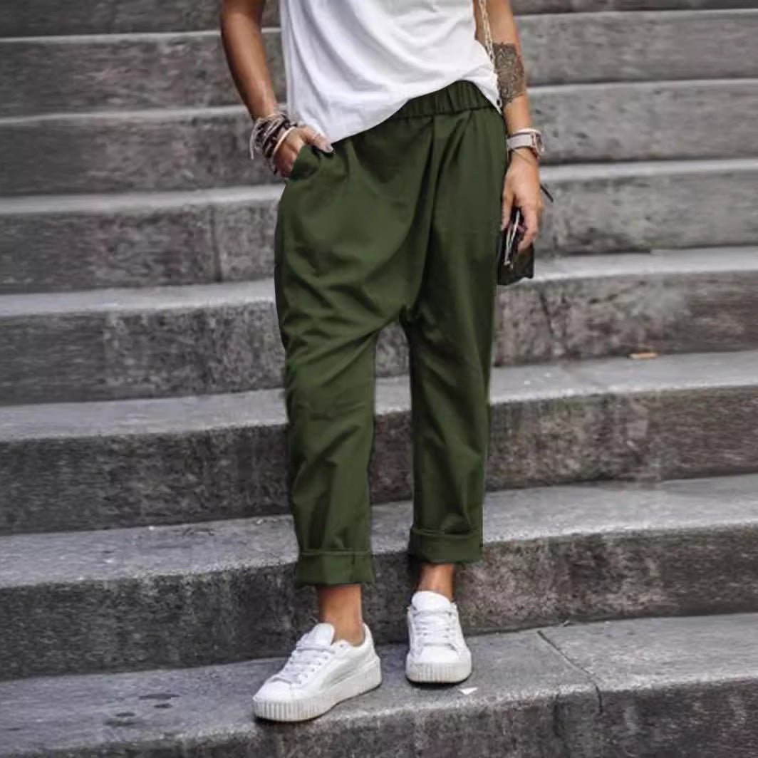 High-waist elastic harem trousers in army green, worn by a model on stone steps, front view with rolled cuffs and side